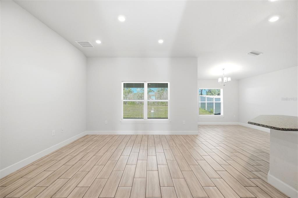 An open-concept room features light wood-look tile flooring, white walls, and recessed lighting — 4355 SUTHERLAND STREET, SPRING HILL, FL