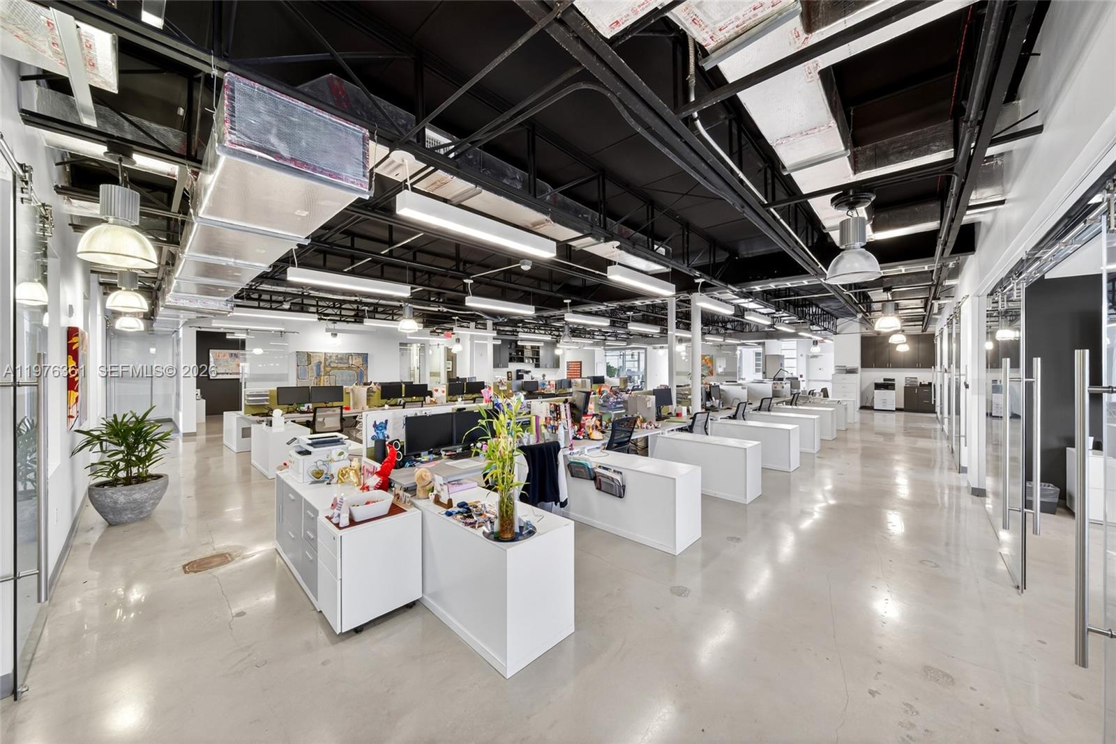 An open-plan office space features white desks, polished concrete floors, and exposed black ceilings — 7630 Biscayne Blvd, Miami FL 33138, MIAMI, FL