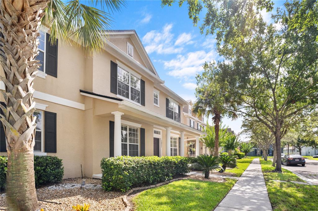 A two-story tan townhouse with black shutters and a front walkway lined with landscaping — 14421 PARADISE TREE DRIVE, ORLANDO, FL