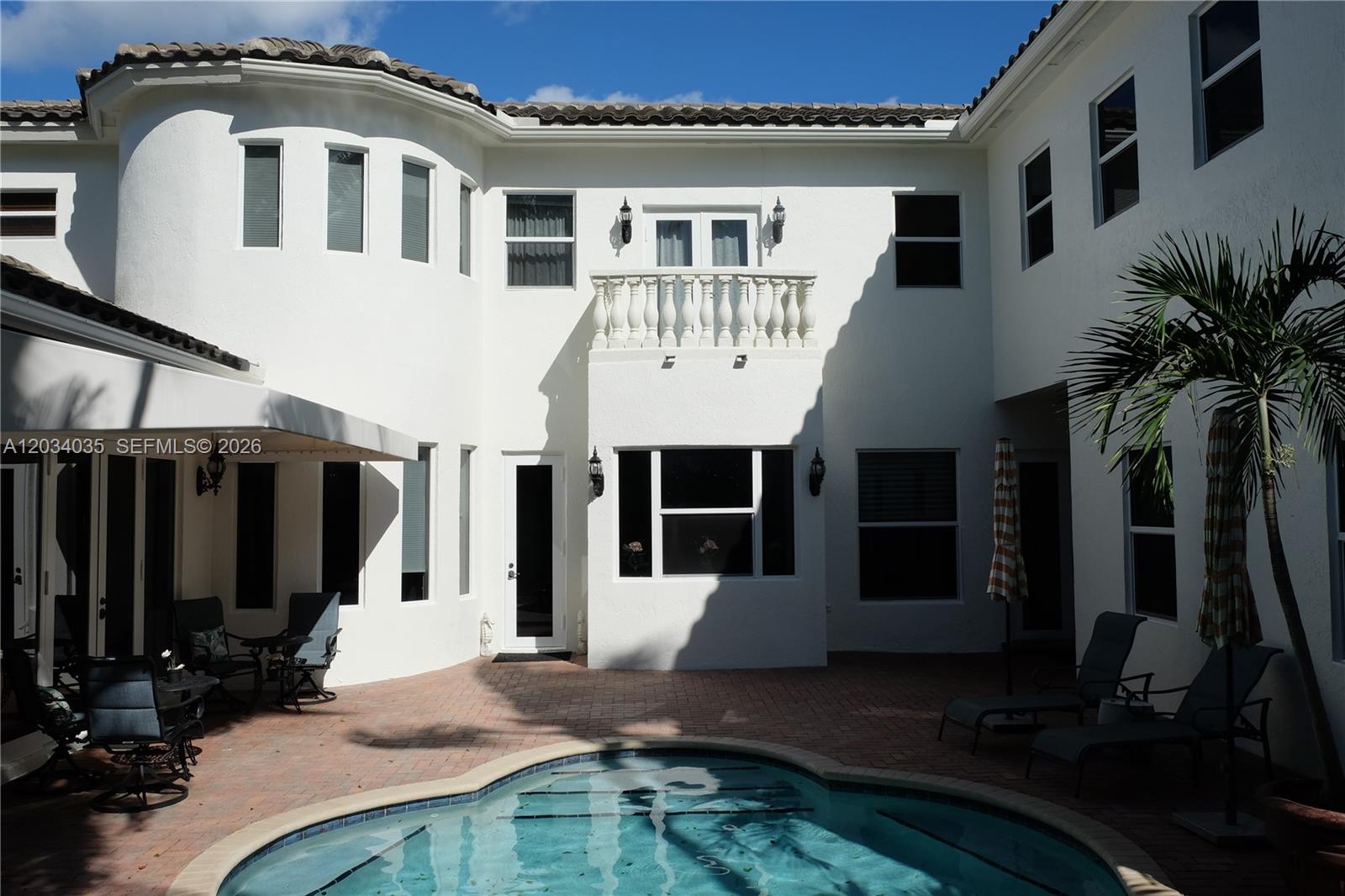 A white two-story house with a balcony overlooks a backyard swimming pool and patio — 375 SW 16th St # 1, Boca Raton FL 33432, BOCA RATON, FL