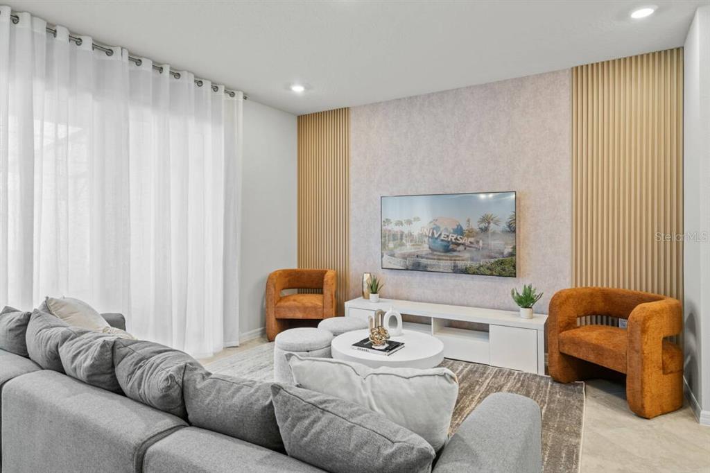 A living room features a gray sofa, two orange armchairs, and a wall-mounted television — 1145 BLUE ISLAND DRIVE, CLERMONT, FL