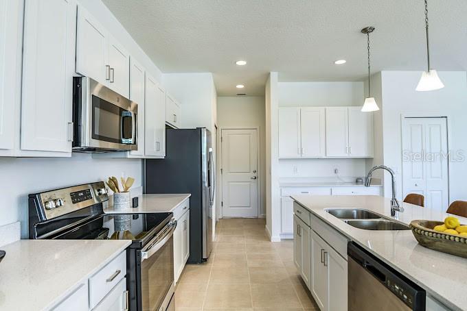 A modern kitchen features white cabinetry, stainless steel appliances, and a central island with seating — 2626 HAM BROWN ROAD UNIT Magdalena, KISSIMMEE, FL