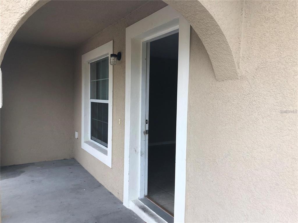 A beige stucco exterior features an arched entryway, a window, and an open doorway — 325 BACCARAT COURT UNIT B, KISSIMMEE, FL