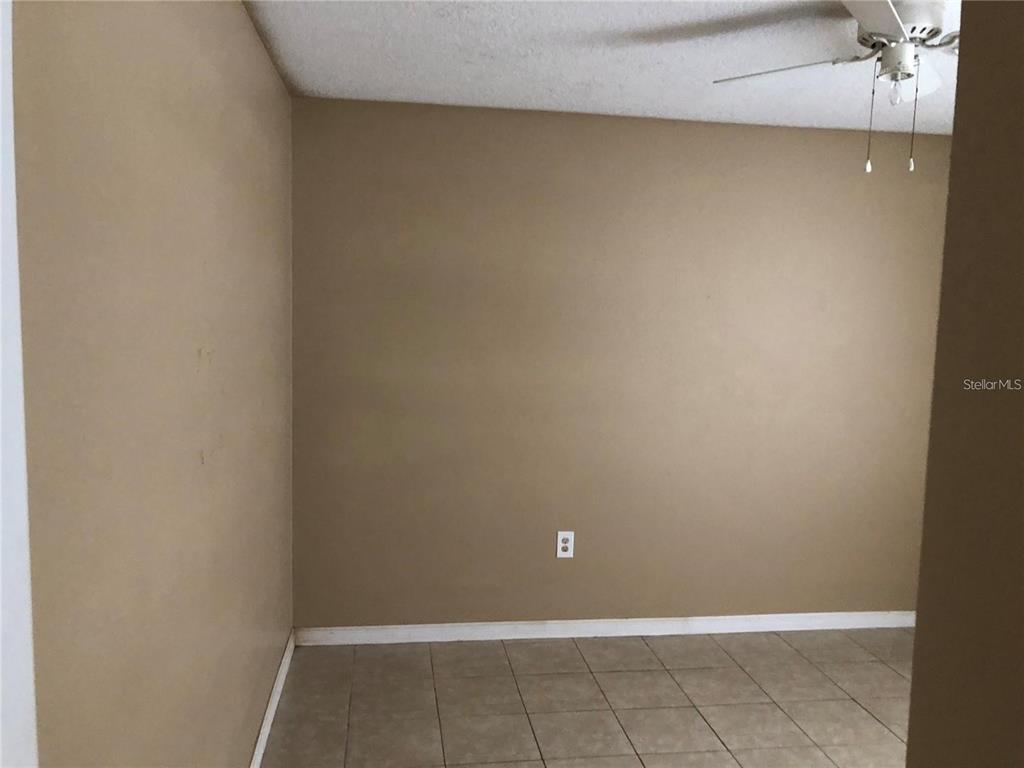 An empty room with tan walls, tile flooring, and a ceiling fan — 325 BACCARAT COURT UNIT B, KISSIMMEE, FL