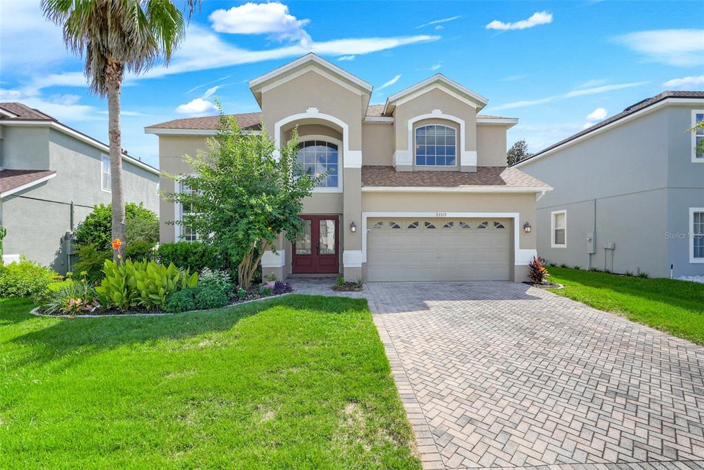 A two-story suburban house with a paved driveway, a two-car garage, and a palm tree — 33519 TERRAGONA DRIVE, SORRENTO, FL