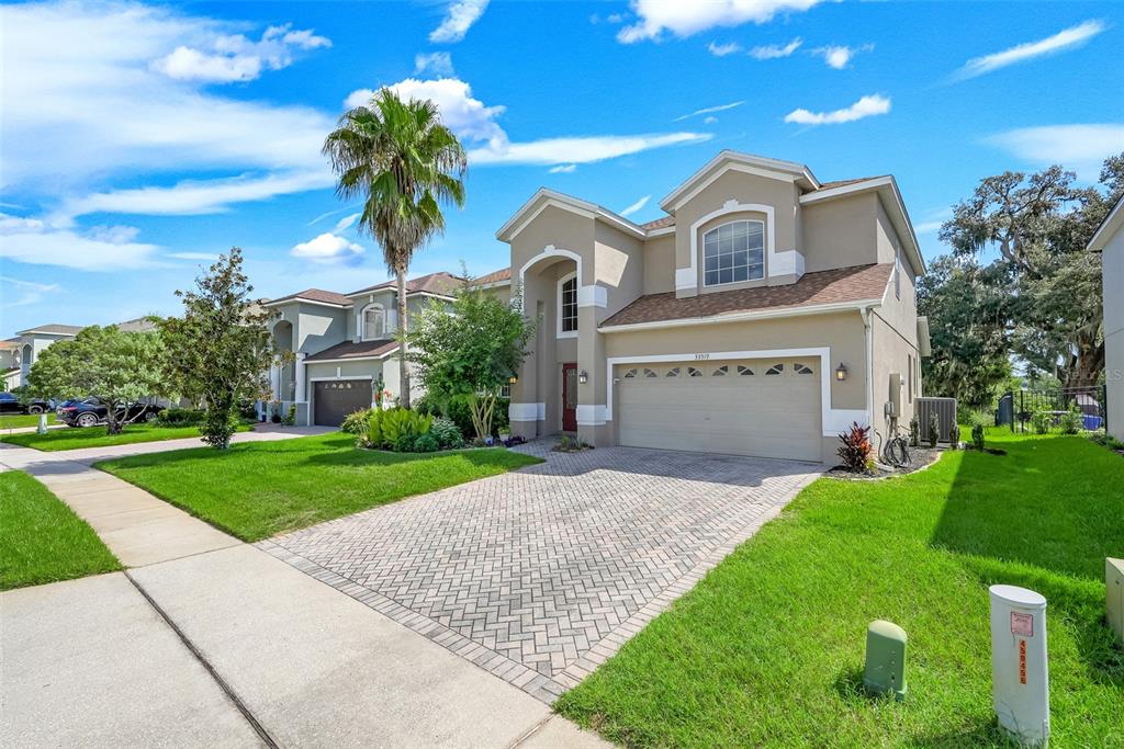 A two-story suburban house with a beige stucco exterior and a brick-paved driveway — 33519 TERRAGONA DRIVE, SORRENTO, FL
