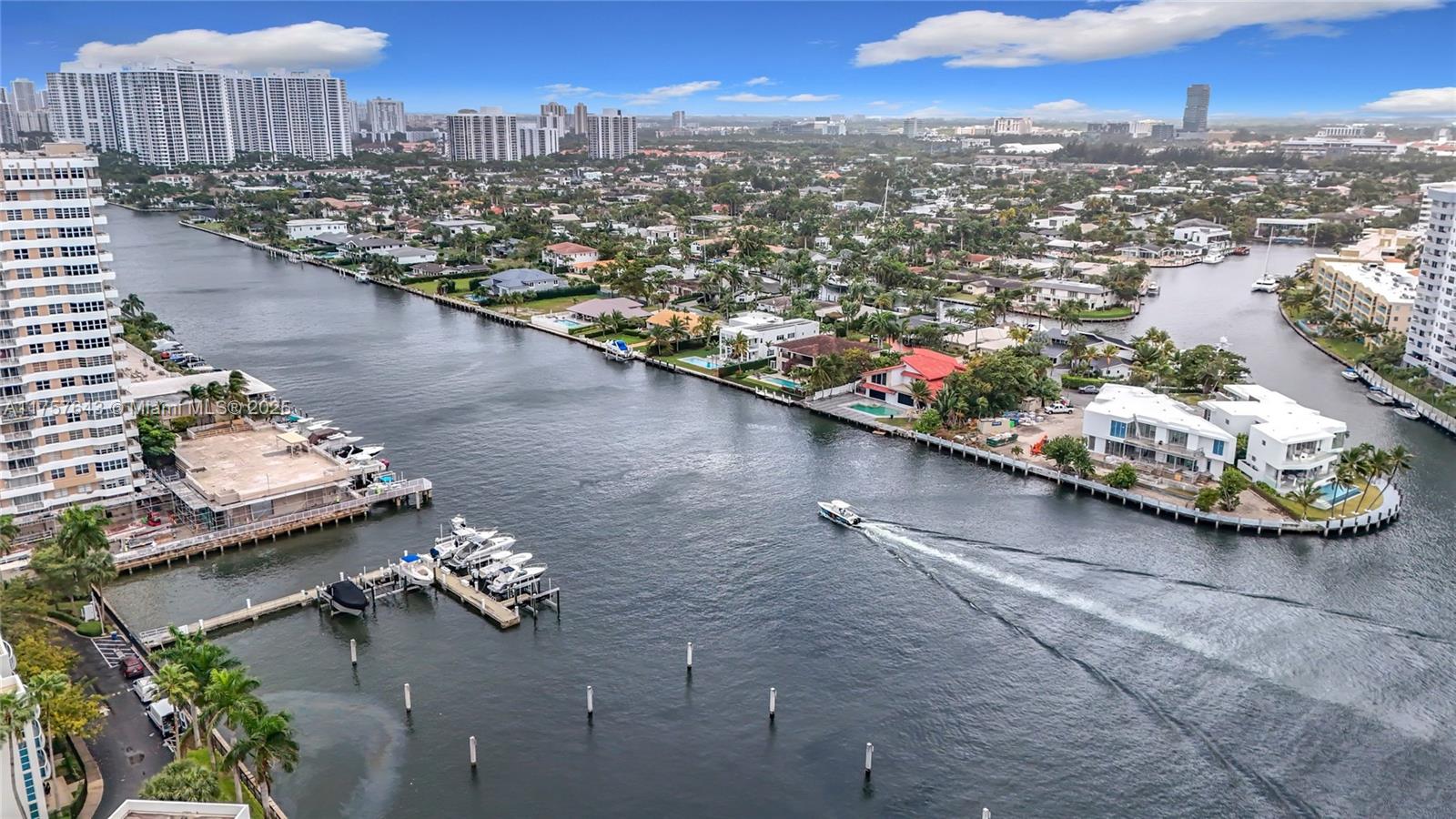 An aerial view shows a waterway with boats, docks, and residential buildings under a cloudy sky — 1945 S Ocean Dr # 605, Hallandale Beach FL 33009, HALLANDALE BEACH, FL