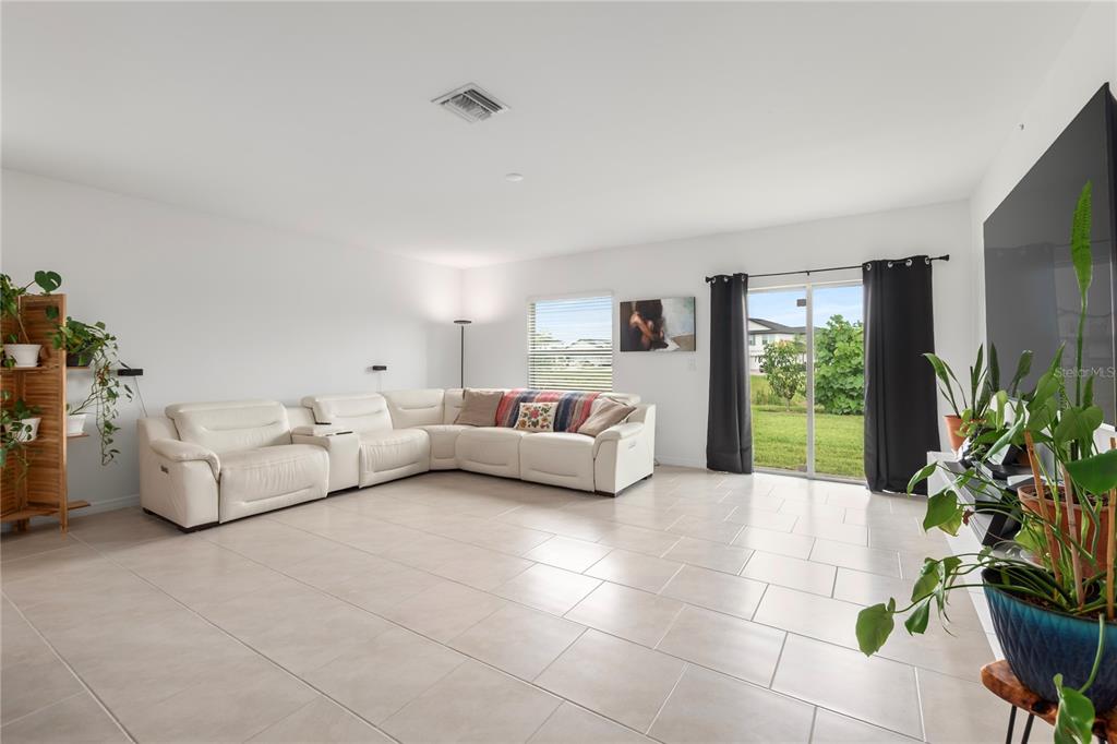 A living room features white tile flooring, a large sectional sofa, and a sliding glass door — 17177 MONTE ISOLA WAY, NORTH FORT MYERS, FL