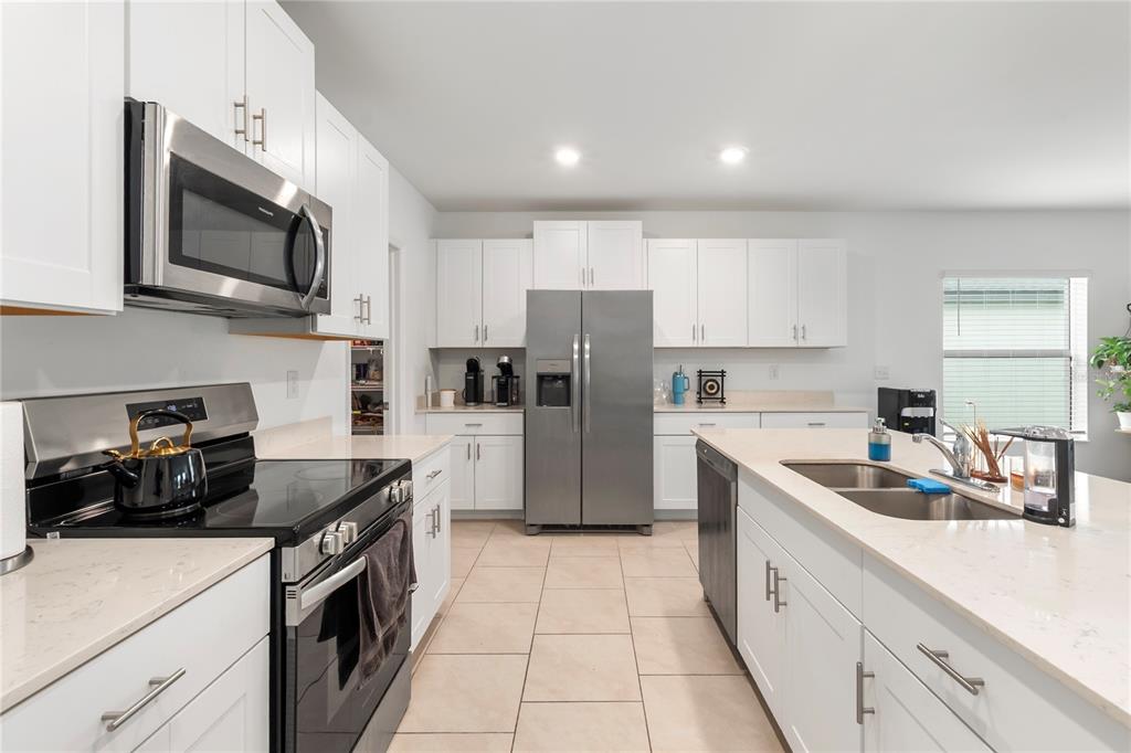A bright, open-concept living and dining area features tile flooring, a dining set, and a sectional — 17177 MONTE ISOLA WAY, NORTH FORT MYERS, FL