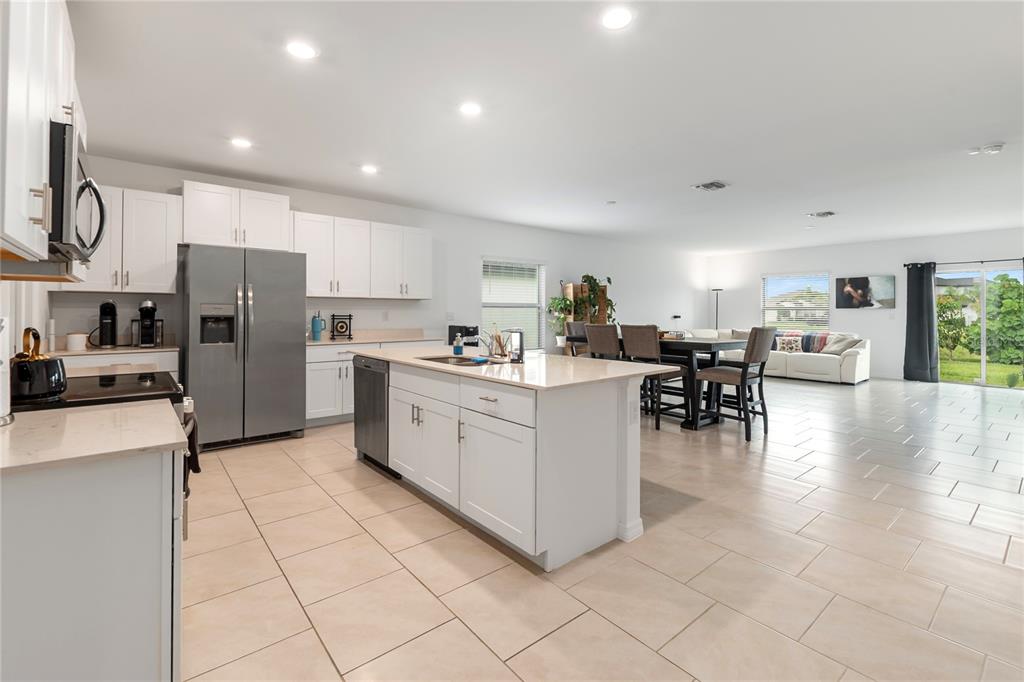 A dining area with a dark wood table and chairs sits before a living room — 17177 MONTE ISOLA WAY, NORTH FORT MYERS, FL