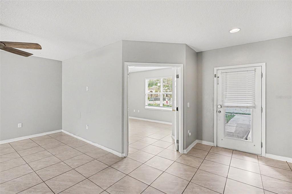 A room with light-colored tile flooring, gray walls, a ceiling fan, and a glass-paneled door — 4957 CASTLE STREET E, KISSIMMEE, FL