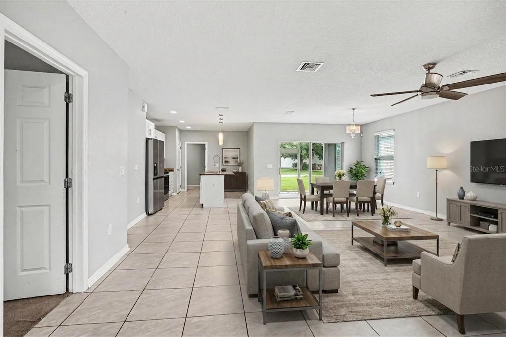 An open-concept living and dining area features light tile flooring, neutral walls, and a kitchen — 4957 CASTLE STREET E, KISSIMMEE, FL