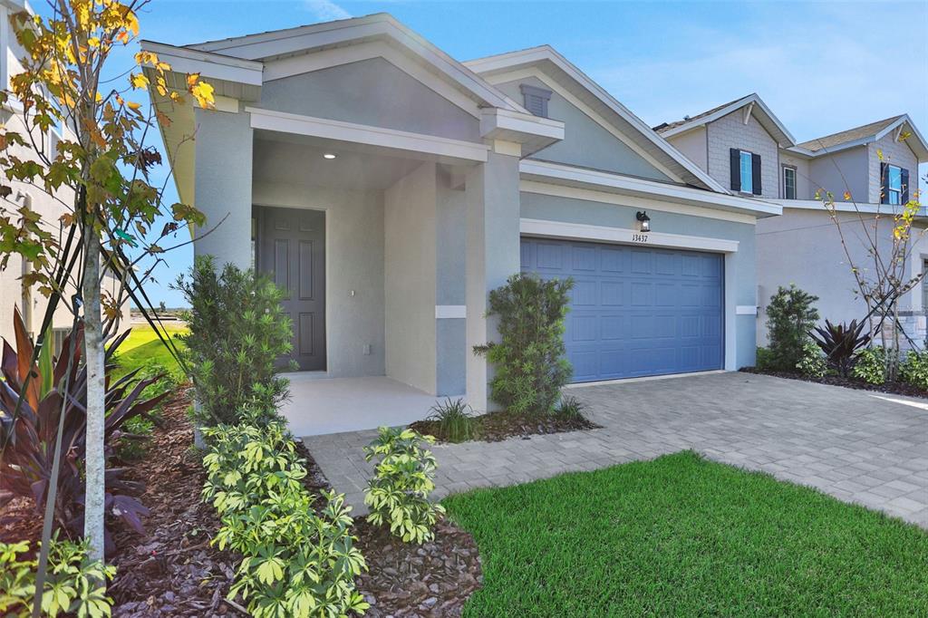 A single-story suburban house features a blue garage door, a covered entryway, and landscaped lawn — 13455 TURNLEAF BOULEVARD, PUNTA GORDA, FL