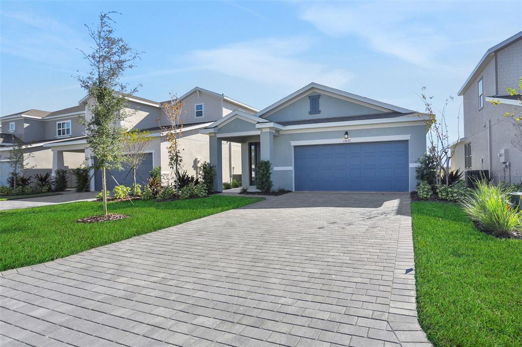A single-story house with a blue garage door and a paved driveway under a blue sky — 13455 TURNLEAF BOULEVARD, PUNTA GORDA, FL