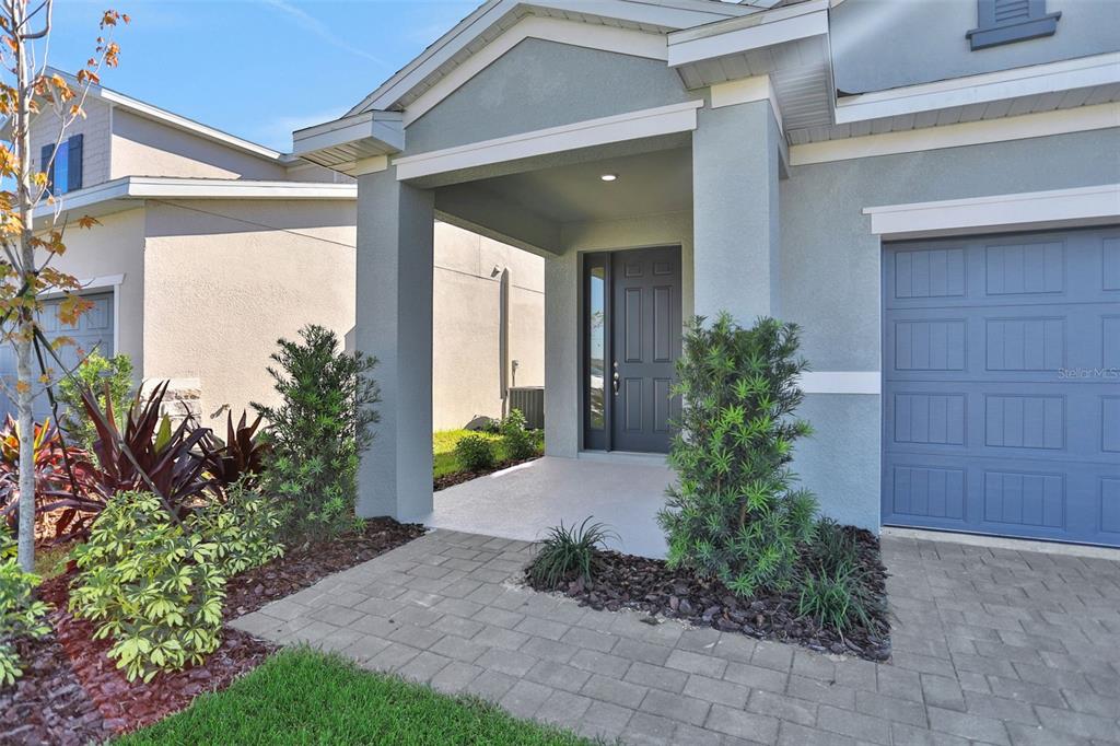 A light blue house exterior features a covered entryway, a dark front door, and a garage — 13455 TURNLEAF BOULEVARD, PUNTA GORDA, FL