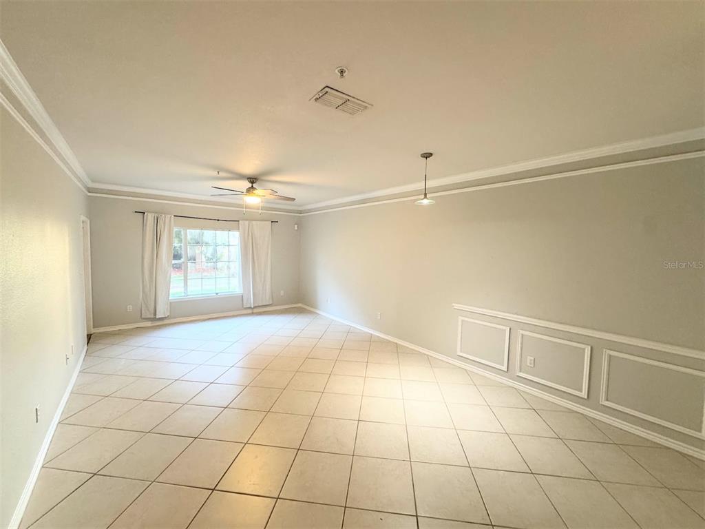 A spacious room with light-colored tile flooring, crown molding, and wainscoting on the wall — 4305 BAYSIDE VILLAGE DRIVE UNIT 104, TAMPA, FL