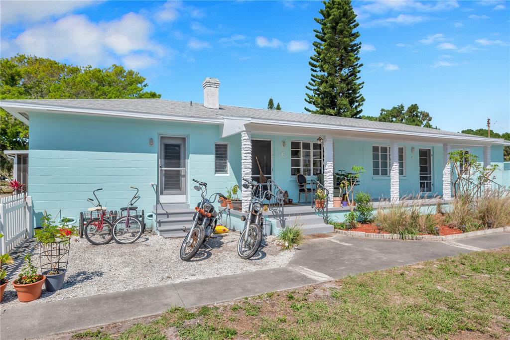 A light blue, single-story house with a covered porch, gravel yard, and two parked motorcycles — 5029 28TH AVENUE S, GULFPORT, FL