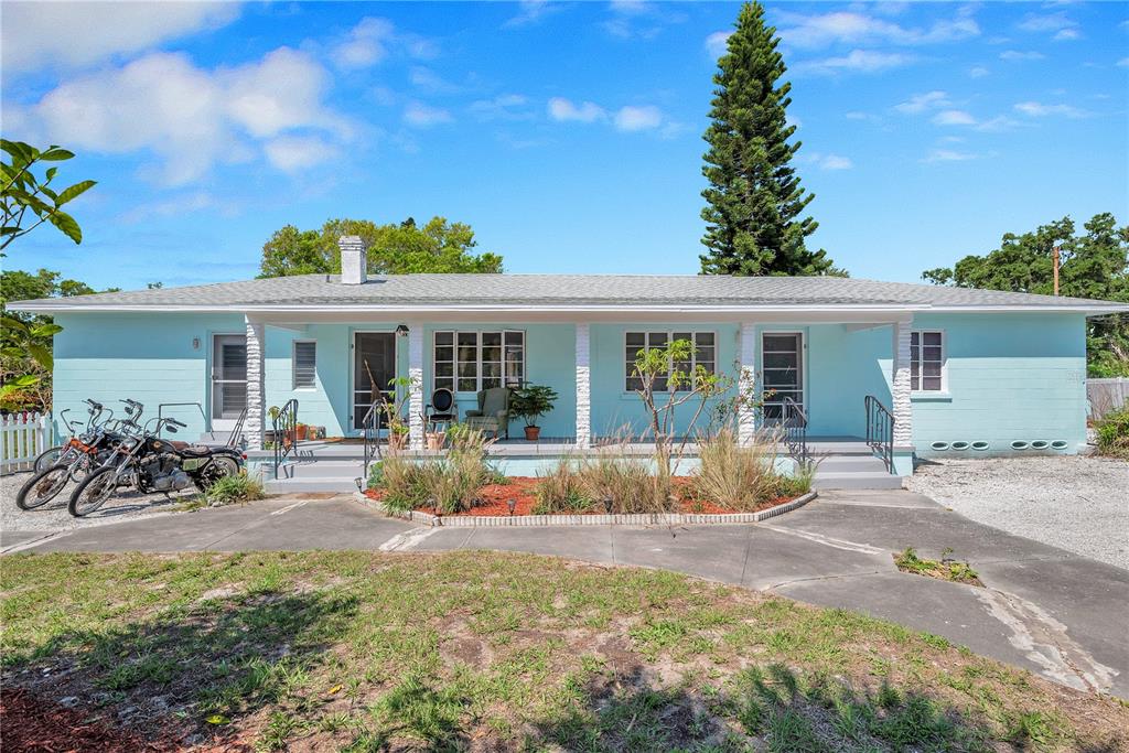 A light blue single-story house with a covered porch, gravel driveway, and parked motorcycles — 5029 28TH AVENUE S, GULFPORT, FL