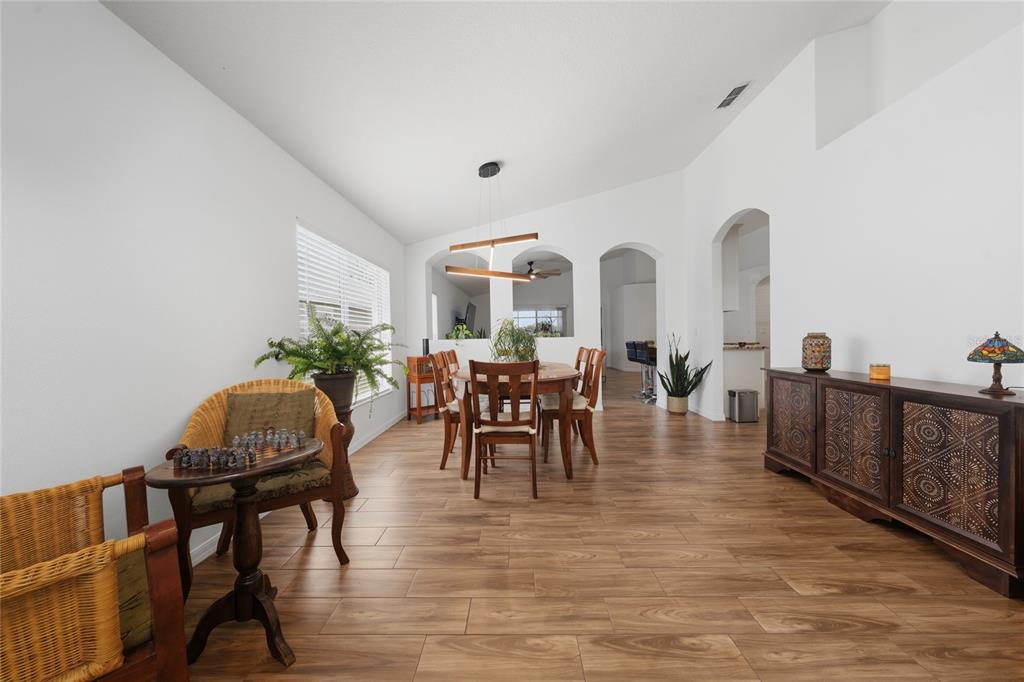 A dining room with wood-look tile flooring, a wooden table, and a decorative sideboard — 13613 BUDWORTH CIRCLE, ORLANDO, FL