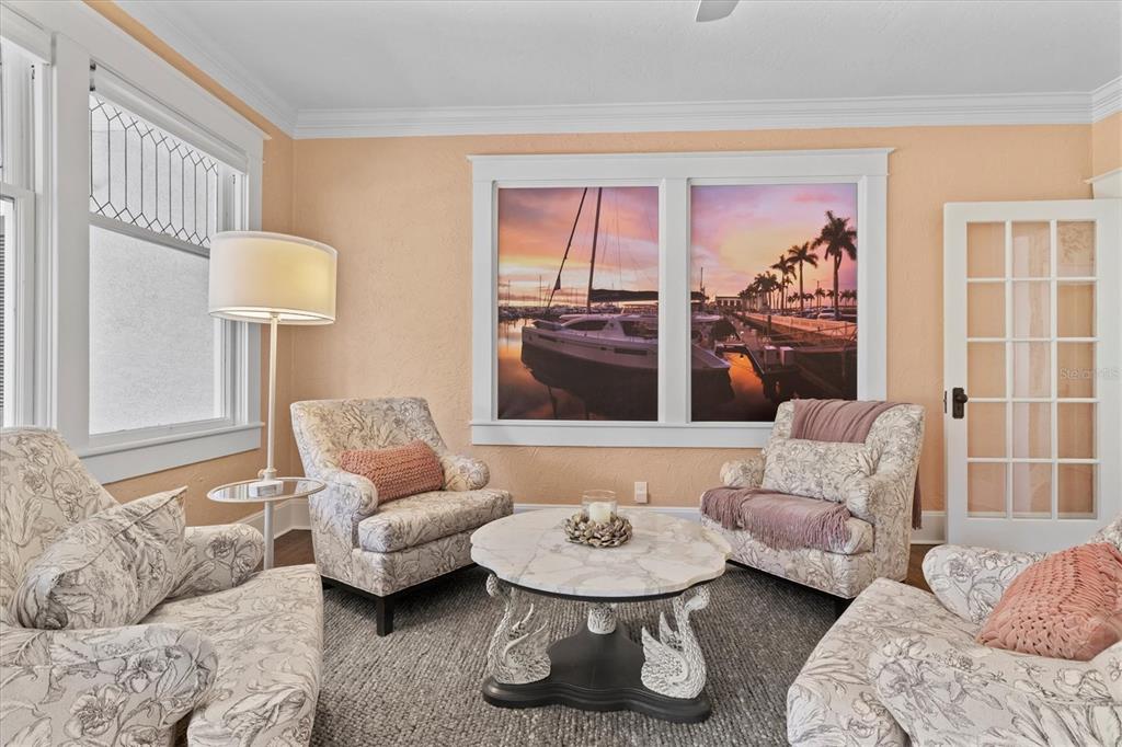 A living room features four patterned armchairs, a swan-base coffee table, and a sunset mural — 1523 1ST AVENUE W, BRADENTON, FL