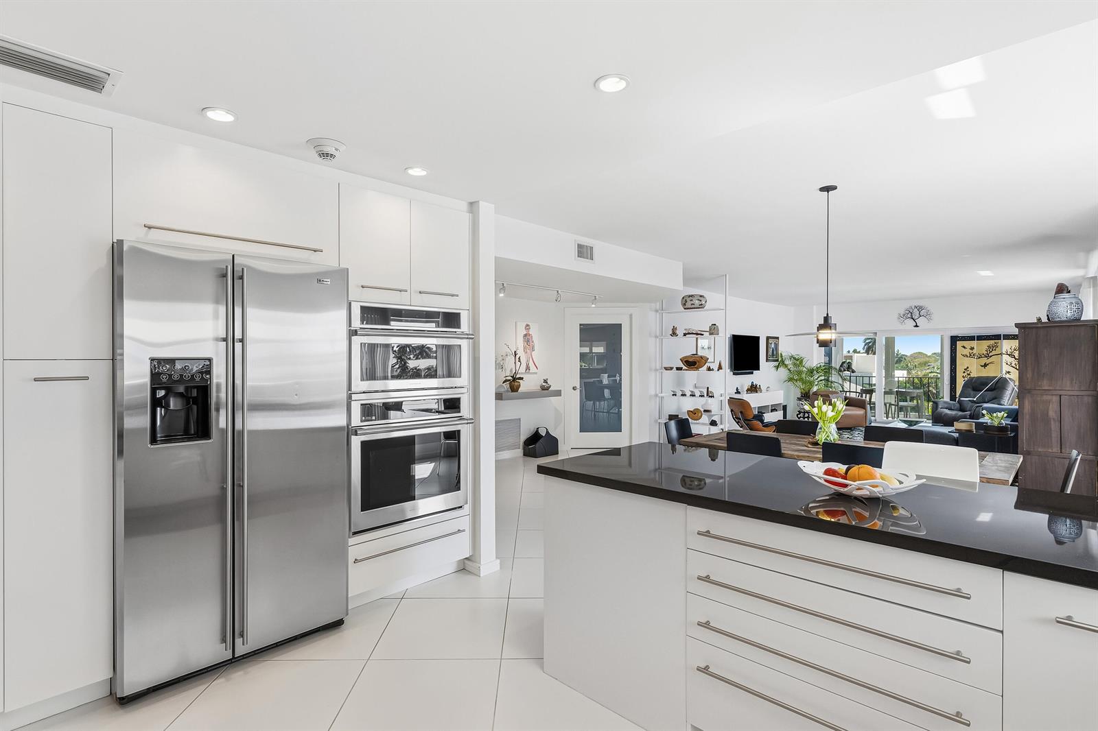 A modern kitchen with white cabinets, stainless steel appliances, and a black island countertop — 200 Macfarlane Drive # 406, Delray Beach FL 33483, DELRAY BEACH, FL