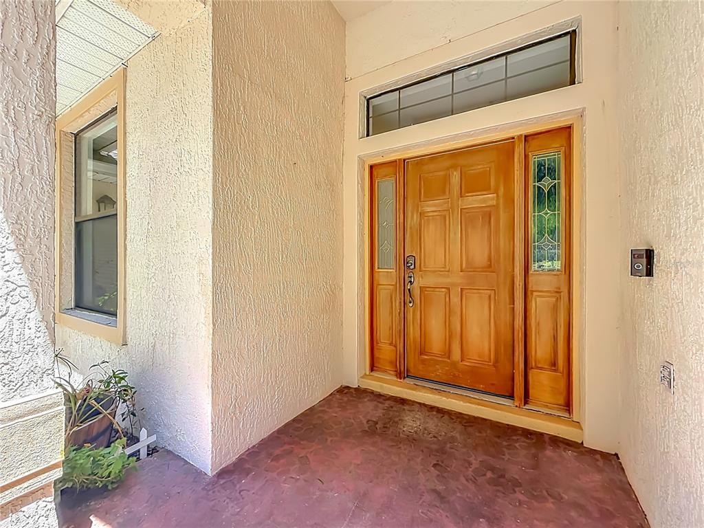 A front entryway features a wooden door with sidelights and a transom window — 14531 WISHING WIND WAY, CLERMONT, FL