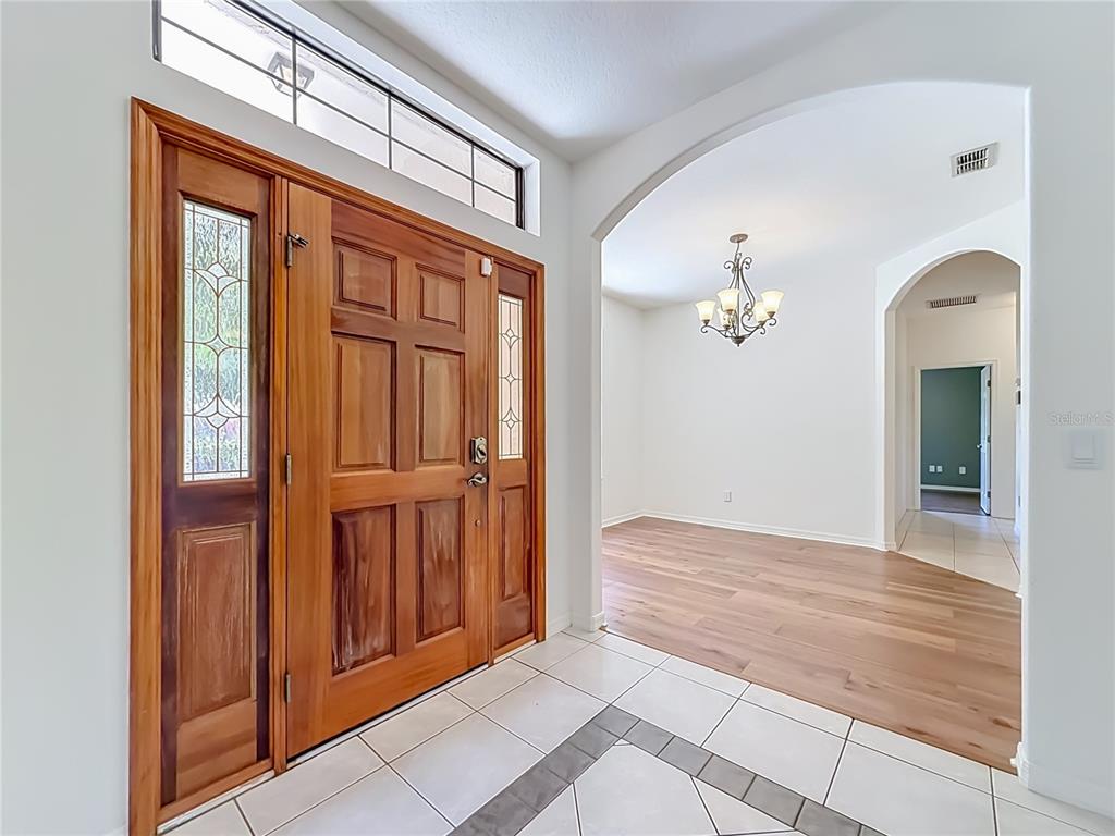 An entryway features a wooden front door with glass panels, tile flooring, and arched openings — 14531 WISHING WIND WAY, CLERMONT, FL