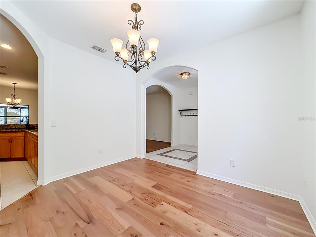 A dining room with hardwood floors, a chandelier, and arched doorways leading to other rooms — 14531 WISHING WIND WAY, CLERMONT, FL