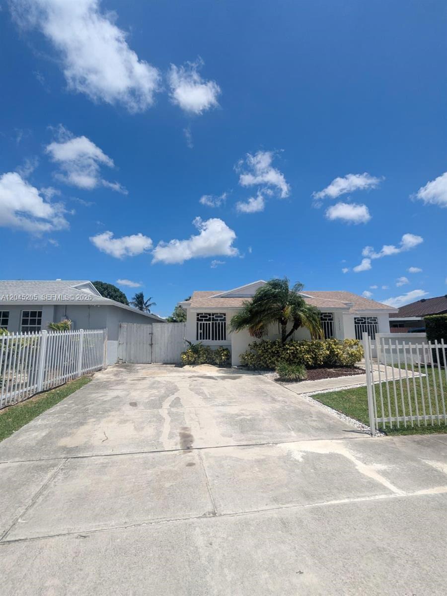 A single-story house features a concrete driveway, white metal fencing, and a palm tree — 12335 SW 193rd St # 12335, Miami FL 33177, MIAMI, FL