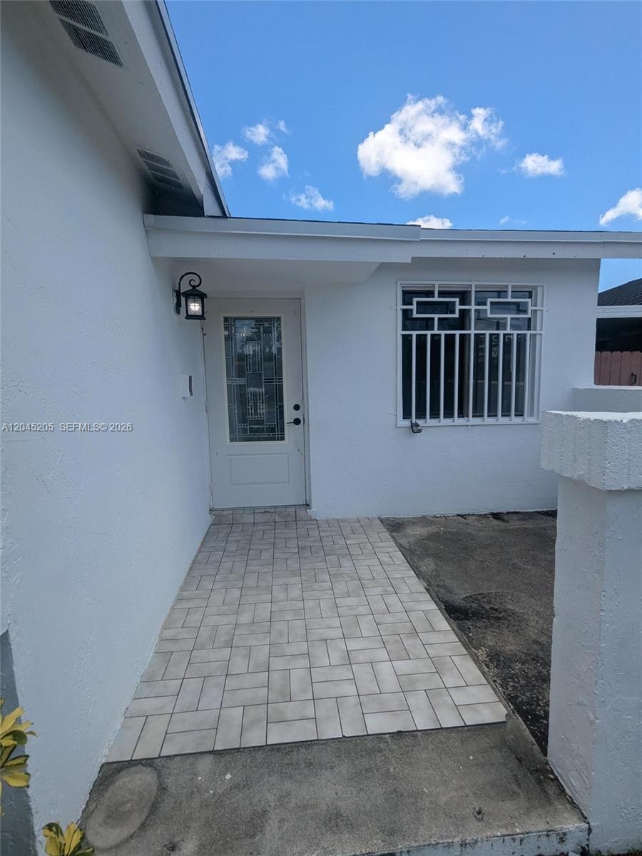 A white exterior entrance features a tiled walkway, a glass-paneled door, and a window with security bars — 12335 SW 193rd St # 12335, Miami FL 33177, MIAMI, FL