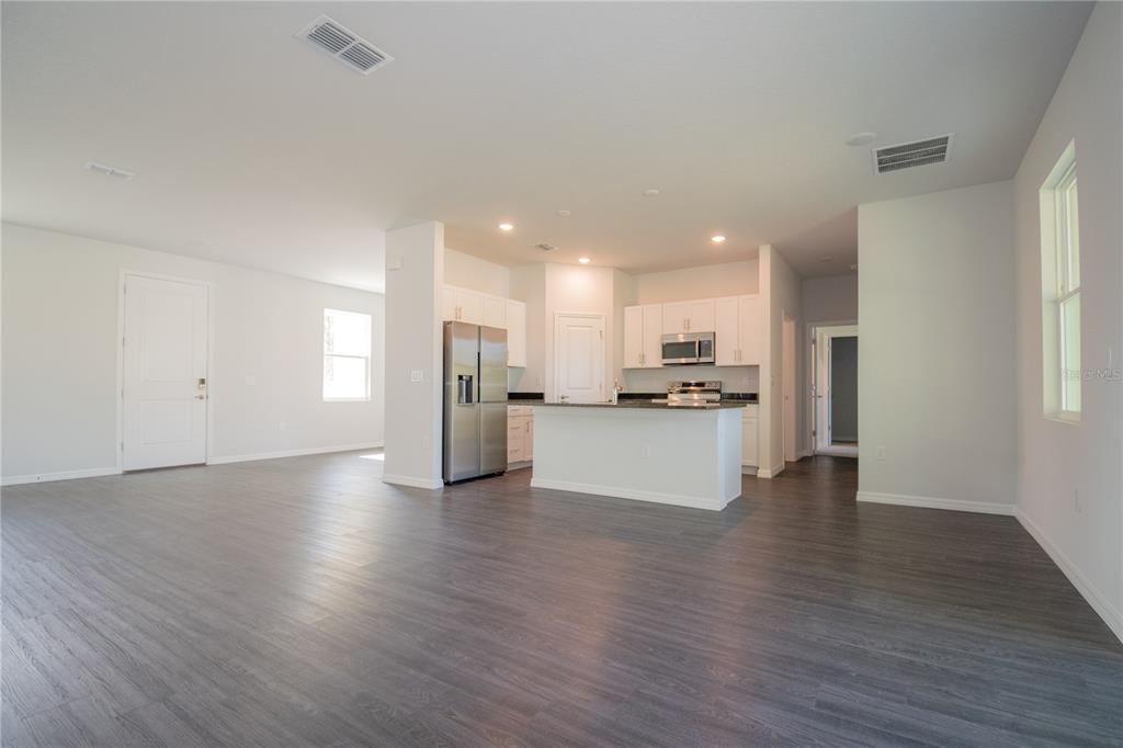 An open-concept kitchen with white cabinets and stainless steel appliances overlooks a large living area — 913 SANGER STREET SE, PALM BAY, FL