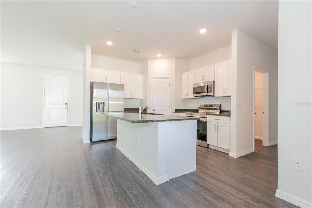 A kitchen with white cabinets, stainless steel appliances, and a dark granite-topped island — 913 SANGER STREET SE, PALM BAY, FL