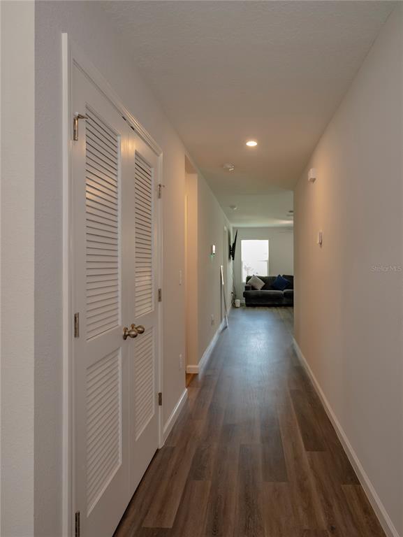 A hallway with wood-look flooring leads to a living area with a sofa and window — 805 TURTLE CREEK DRIVE S, JACKSONVILLE, FL