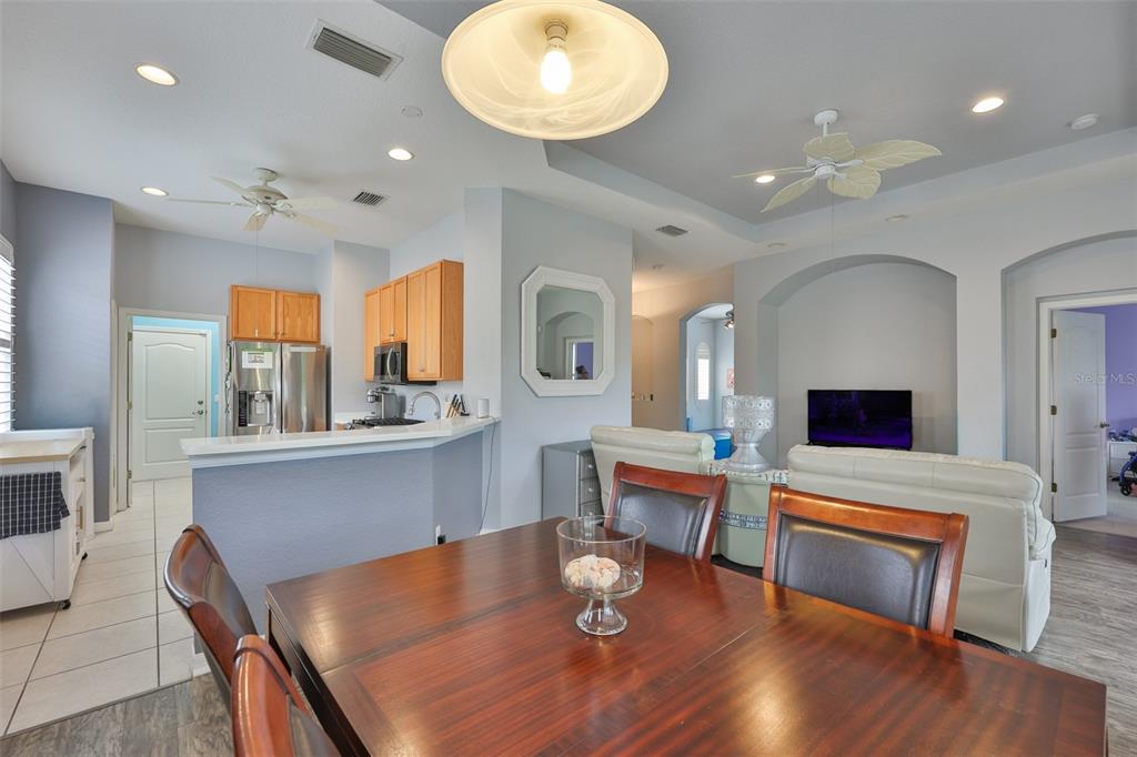 A dining area with a wooden table sits before an open kitchen and living room — 1050 REGAL MANOR WAY, SUN CITY CENTER, FL