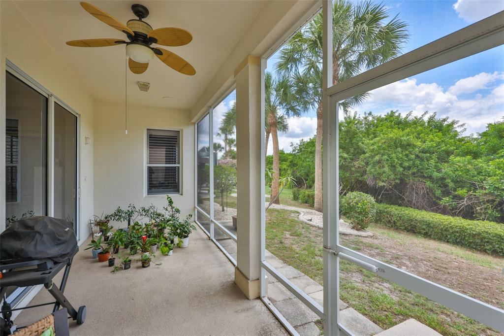 A screened-in patio features a ceiling fan, a grill, potted plants, and a backyard view — 1050 REGAL MANOR WAY, SUN CITY CENTER, FL