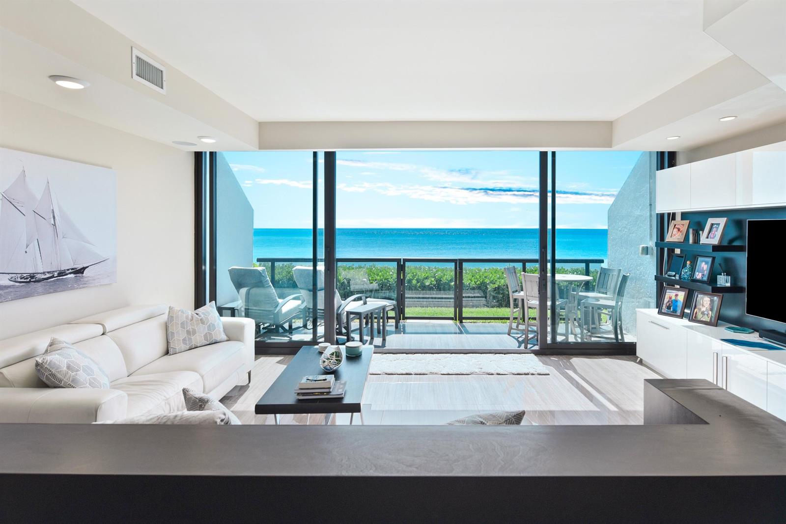 A living room with a white sofa, coffee table, and large sliding doors overlooking the ocean — 3115 S Ocean Boulevard # 103, Highland Beach FL 33487, HIGHLAND BEACH, FL