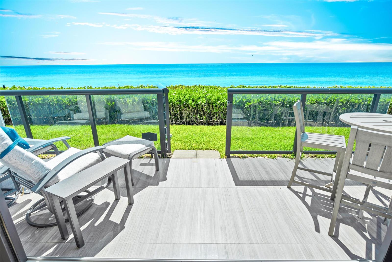 A patio with outdoor furniture overlooks a grassy lawn and the ocean — 3115 S Ocean Boulevard # 103, Highland Beach FL 33487, HIGHLAND BEACH, FL