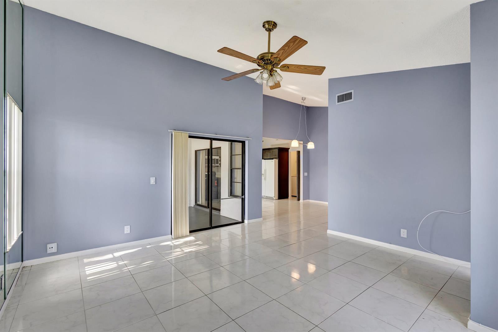 A spacious room with light blue walls, white tile flooring, and a ceiling fan — 4385 Willow Brook Circle, West Palm Beach FL 33417, WEST PALM BEACH, FL