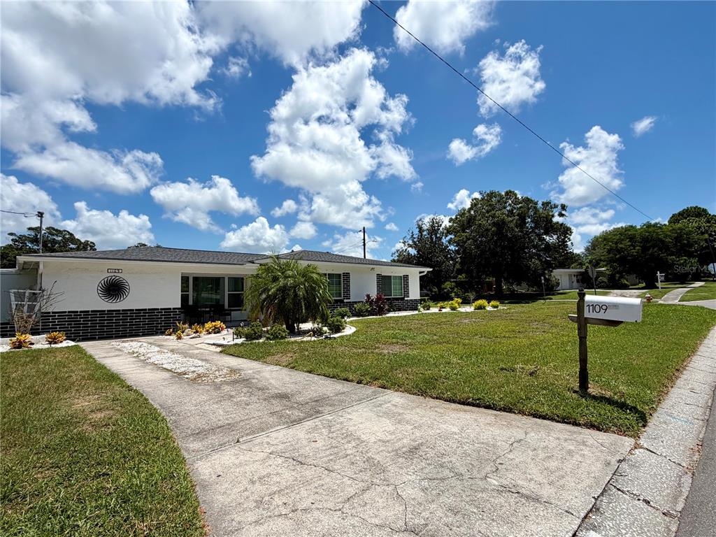 A single-story house with a white facade, dark brick base, and a concrete driveway — 1109 S BETTY LANE, CLEARWATER, FL
