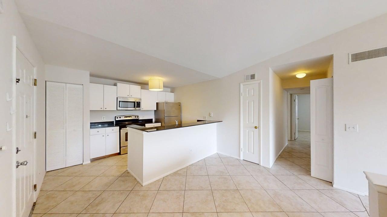 An open-concept kitchen features white cabinets, stainless steel appliances, and a black granite breakfast bar — 1885 Palm Cove Boulevard # 307, Delray Beach FL 33445, DELRAY BEACH, FL
