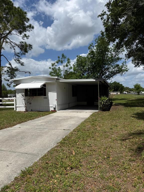 A white mobile home features a concrete driveway, a carport, and an attached window awning — 37021 PAULS DRIVE, ZEPHYRHILLS, FL