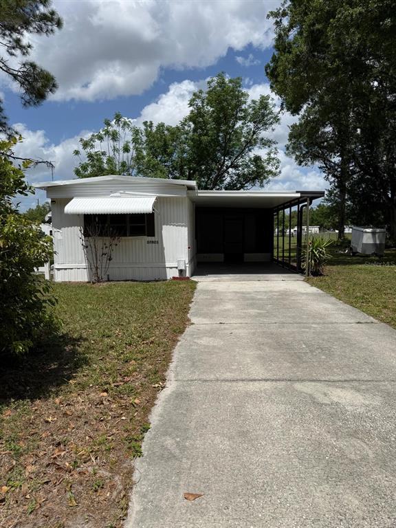 A white mobile home features a concrete driveway and an attached covered carport — 37021 PAULS DRIVE, ZEPHYRHILLS, FL
