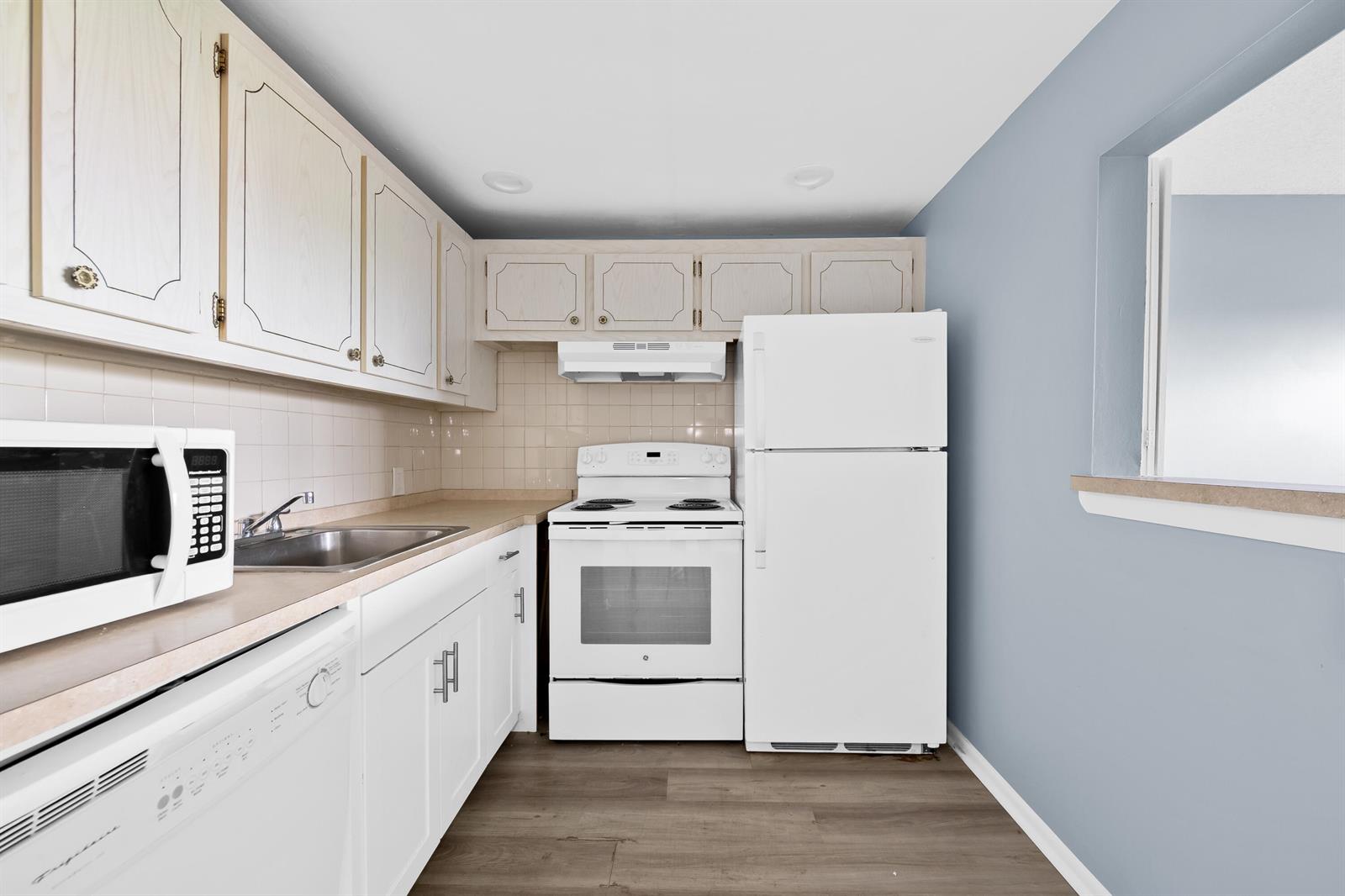 A kitchen features white appliances, light wood cabinets, a stainless steel sink, and blue walls — 148 Preston Way # 148, Boca Raton FL 33434, BOCA RATON, FL