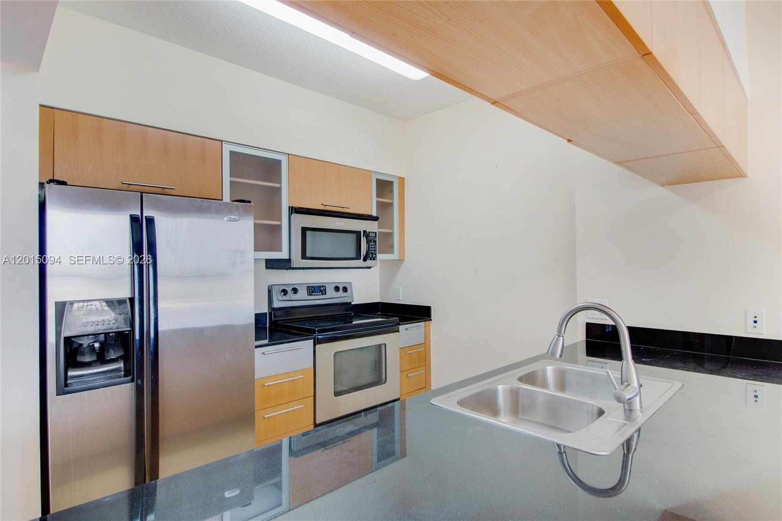 A kitchen features stainless steel appliances, light wood cabinets, and a black granite countertop — 1750 N Bayshore Dr # 3111, Miami FL 33132, MIAMI, FL