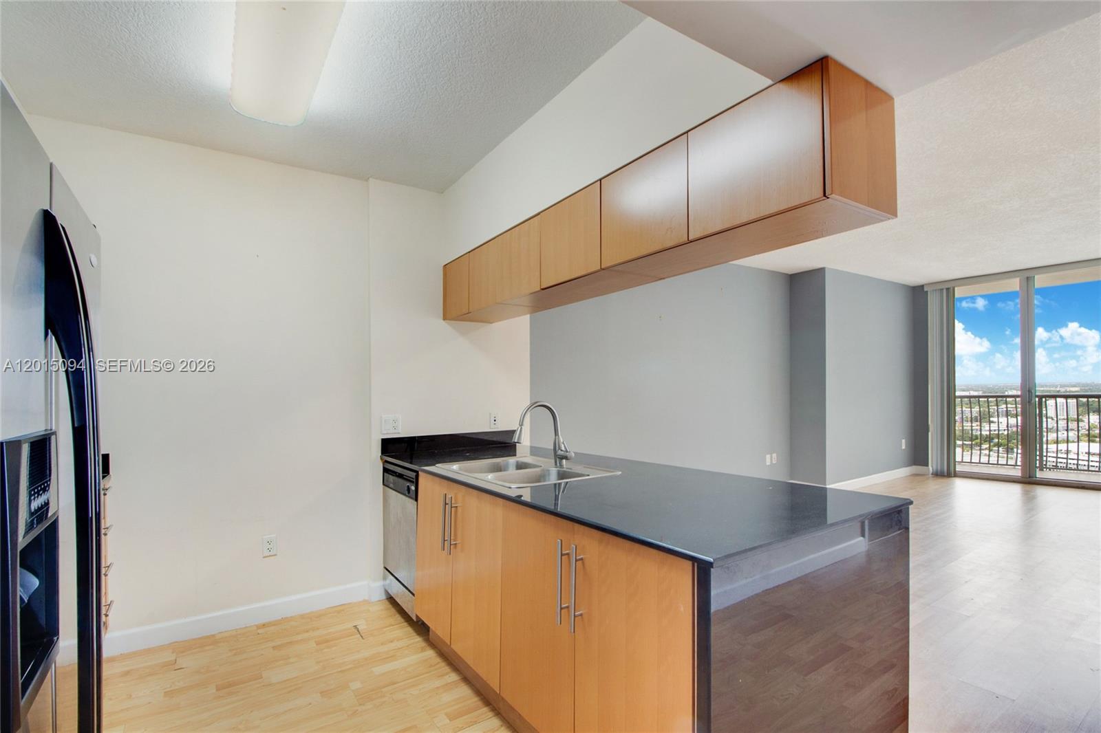 A kitchen features light wood cabinets, black countertops, and a stainless steel dishwasher — 1750 N Bayshore Dr # 3111, Miami FL 33132, MIAMI, FL