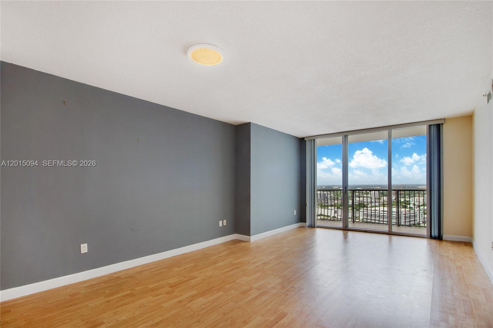 An empty room features gray walls, light wood flooring, and a balcony with city views — 1750 N Bayshore Dr # 3111, Miami FL 33132, MIAMI, FL