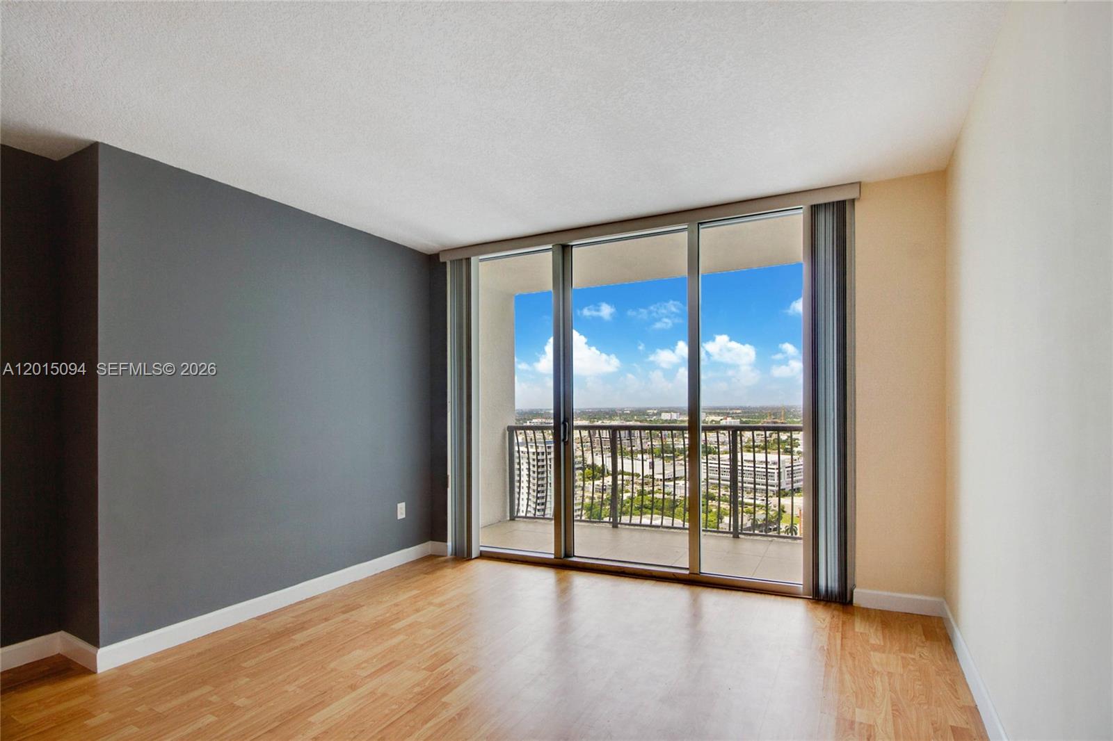 An empty room features light wood flooring, a dark gray accent wall, and a balcony — 1750 N Bayshore Dr # 3111, Miami FL 33132, MIAMI, FL