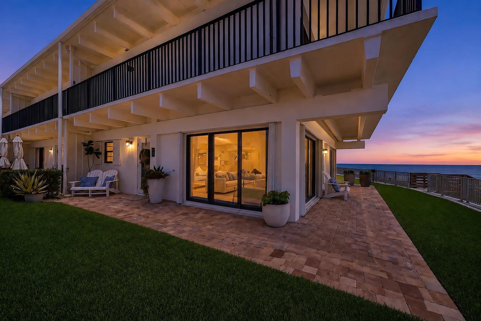 A paved patio with outdoor furniture sits outside a white building overlooking the ocean — VERO BEACH, FL