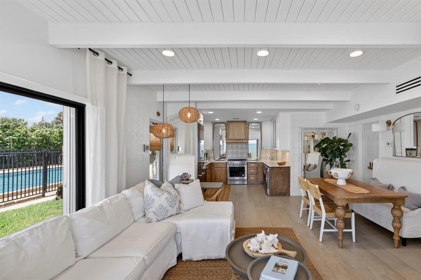 An open-concept living and dining area features white shiplap ceilings, wood floors, and a kitchen — VERO BEACH, FL