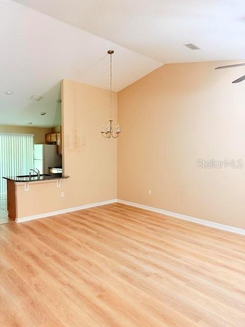 A dining area with light wood-look flooring, a chandelier, and a view of the kitchen — 113 BRUNSWICK LANE UNIT A, PALM COAST, FL